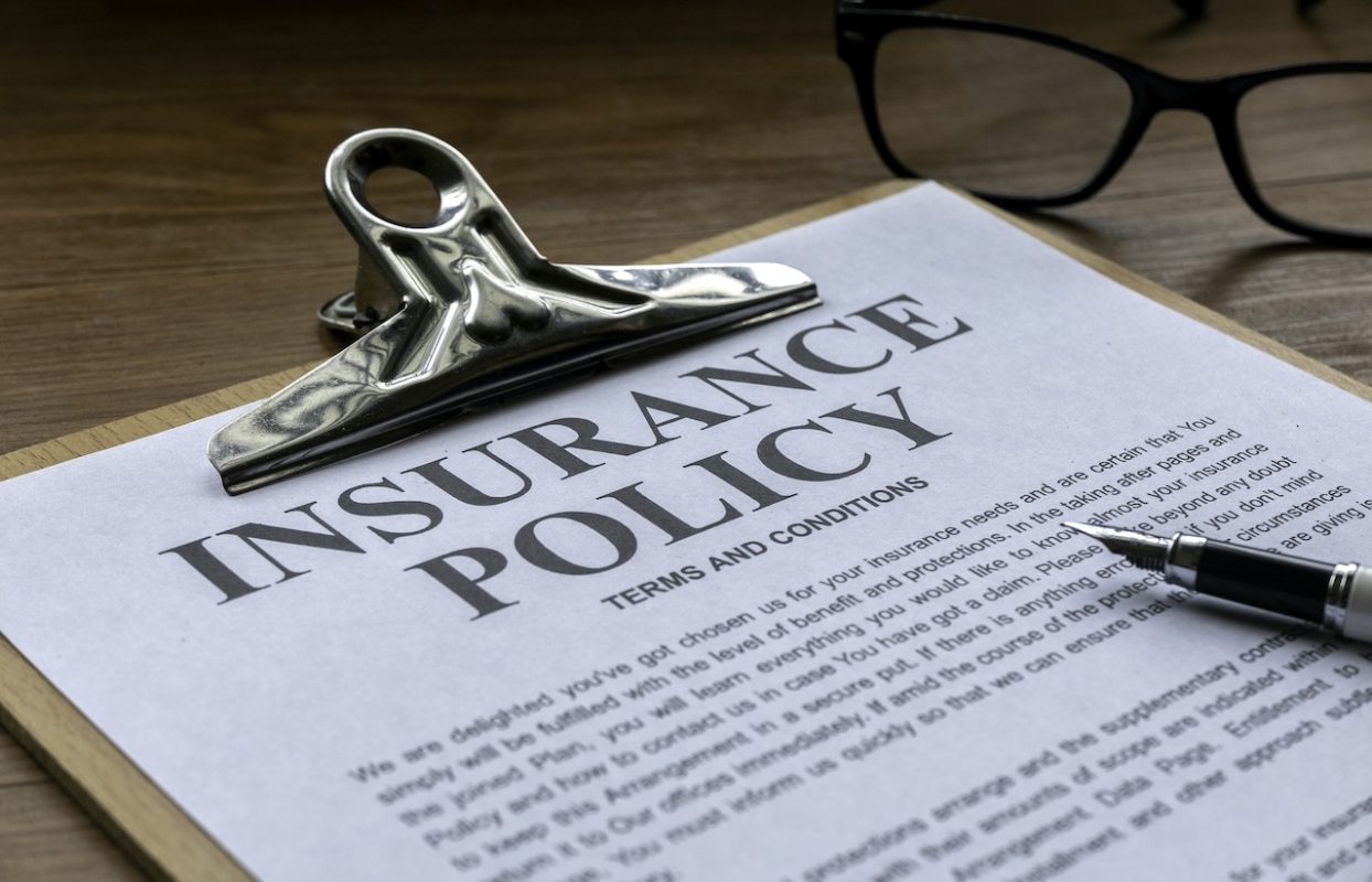 insurance policy on clipboard with pen and glasses
